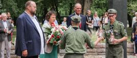Na fotografii moment przekazania harcerzom wiązanki oraz dwóch płonących zniczy harcerzom ZHP