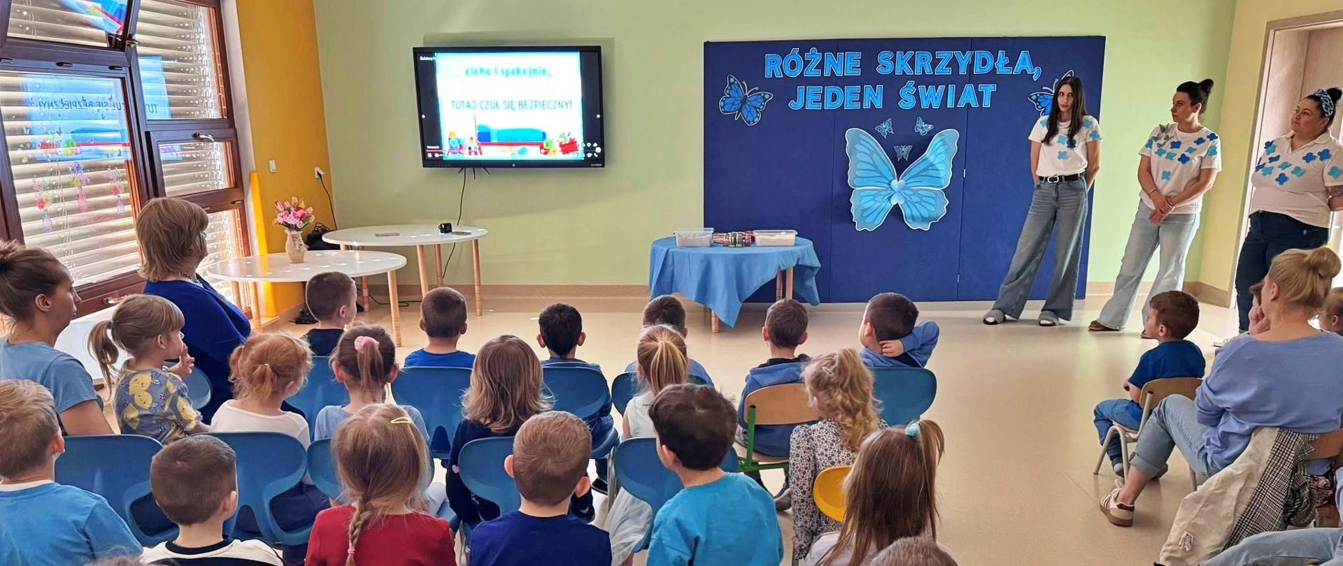 grupa dzieci ubranych w błekitno-niebieskich ubraniach podczas prelekcji