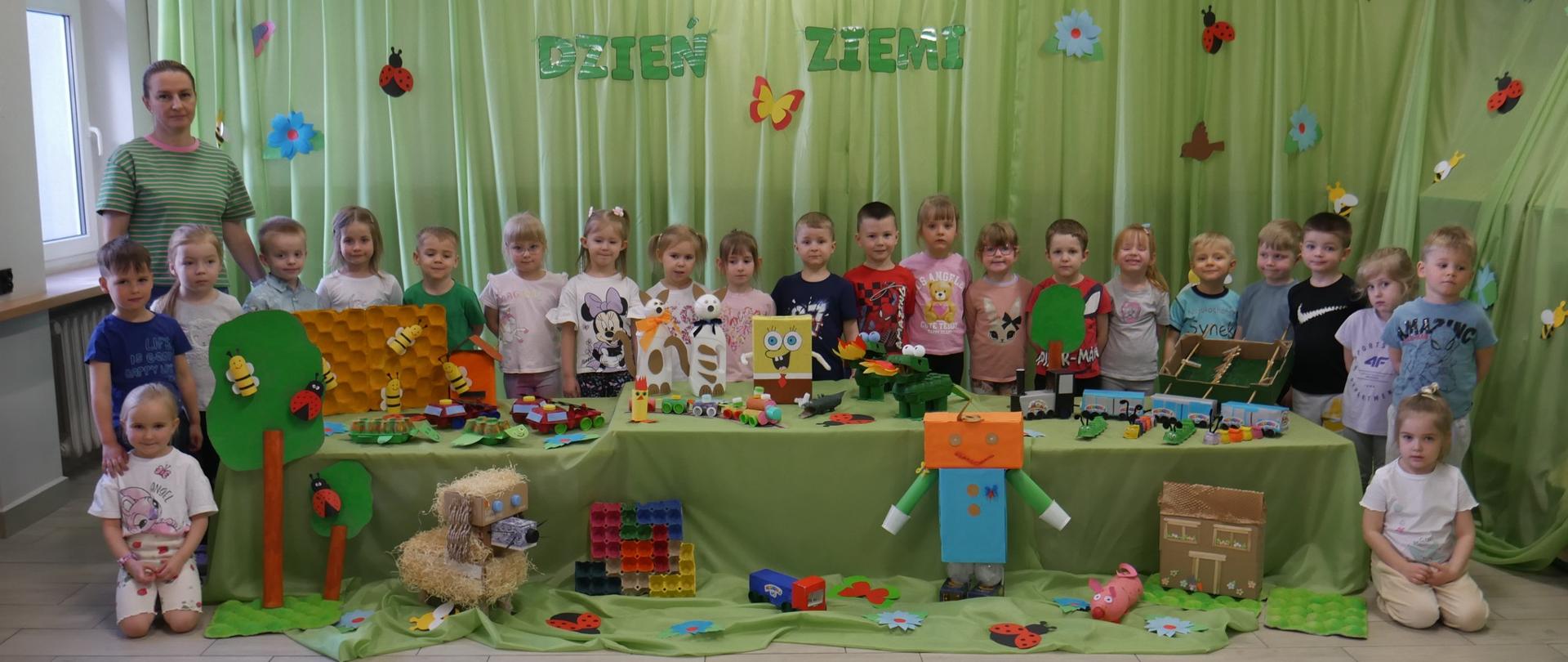 1 osoba dorosła i grupa dzieci przy wystawie zabawek z materiałów wtórnych 