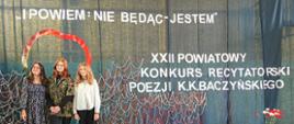3 stojąca obok siebie dziewczyny. Za nimi biały napis: i powiem nie będąc jestem. XXII Powiatowy Konkurs Recytatorski Poezji K.K. Baczyńskiego