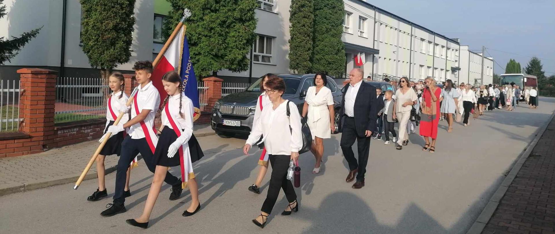 poczet sztandarowi i ludzie idący za nim ulicą