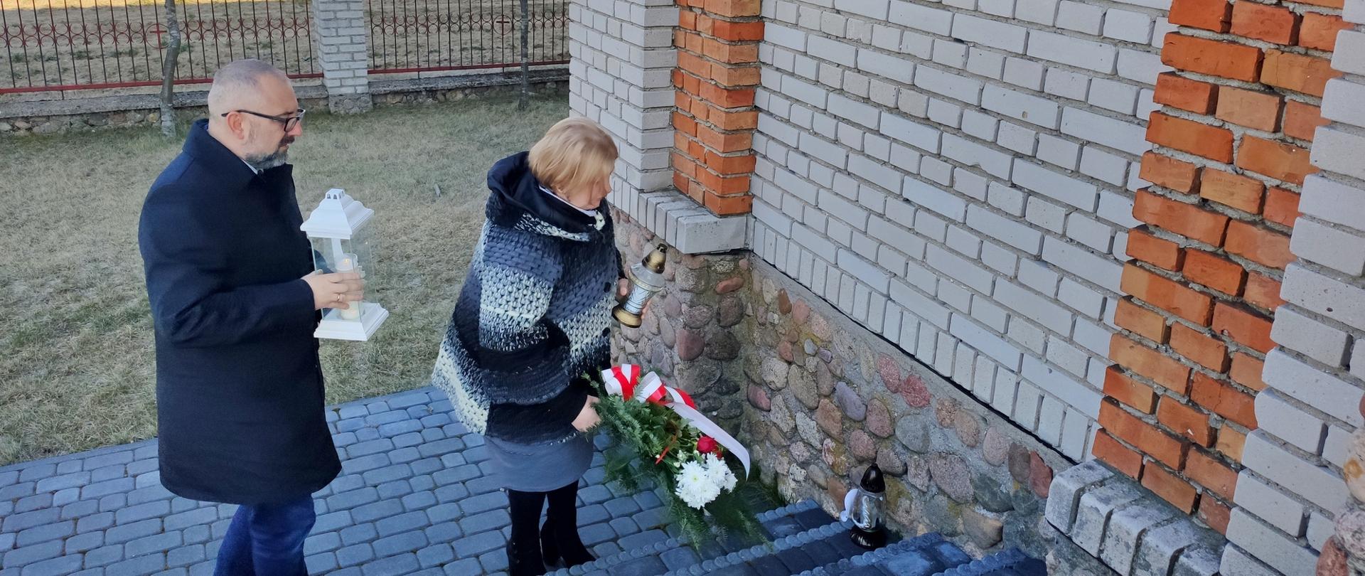 Starosta Bieńkowskia i Anna Karwowska składają wieniec i znicz pod tablicą pamiątkową
