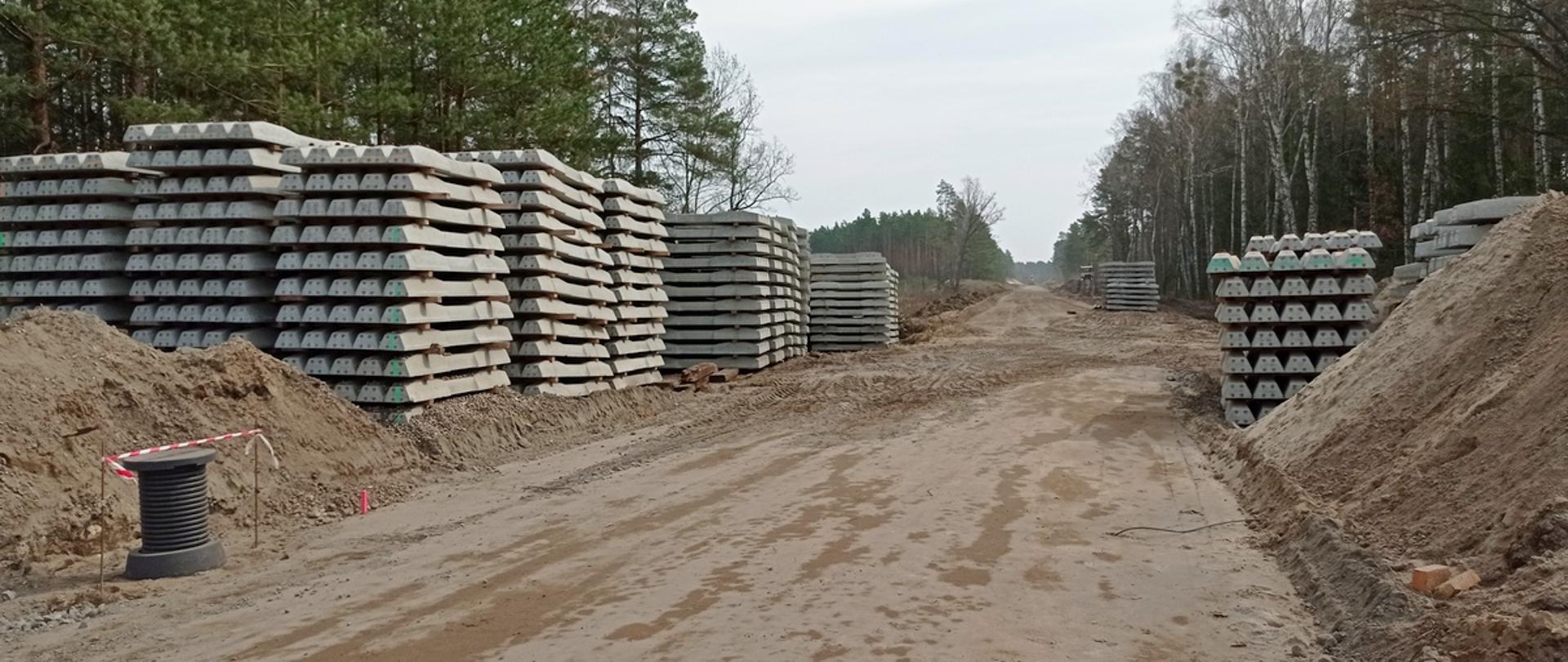 Zdjęcie przedstawia podtorze w fazie przygotowań, odświeżony i utwardzony wykop oraz przygotowane betonowe podkłady do przytwierdzania szyn w miejscowości Parciaki-Stacja w gminie Jednorożec. Prowadzone prace są elementem modernizacji linii kolejowej nr 35 Ostrołęka-Chorzele.