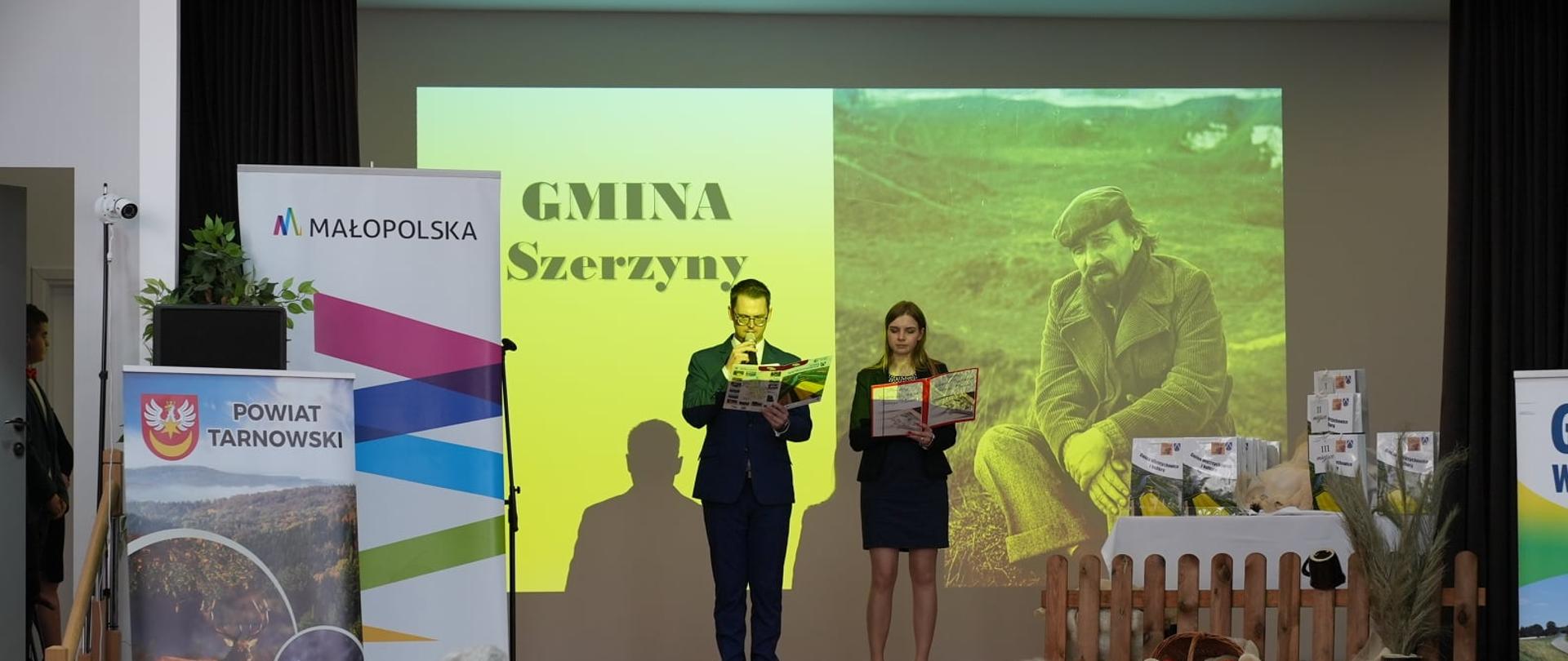 Wójt Gminy Wietrzychowice i Zastępca Dyrektora Gminnego Centrum Kultury na tle zdjęcia poety Tadeusza Nowaka