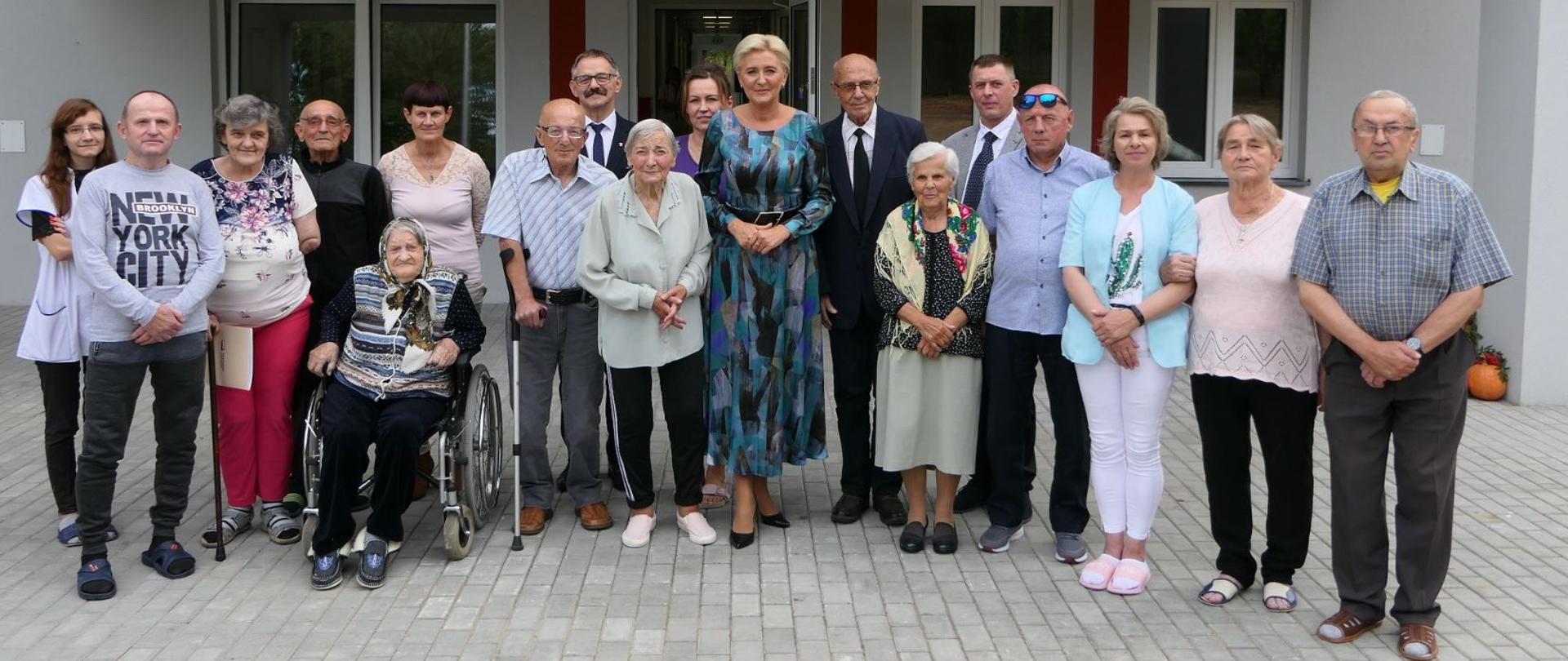 Pani Prezydentowa, Starosta Lipski, podopieczni i personel placówki - zdjęcie grupowe. W tla front budynku Centrum Opiekuńczo-Mieszkalnego.