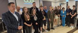 Na zdjęciu widzimy grupę uczniów ze szkół ponadpodstawowych (dziewczęta i chłopcy), którzy zostali uhonorowani statuetkami oraz medalami wraz z przedstawicielami samorządów powiatowego oraz miejskiego, nauczycielami i organizatorami zawodów.