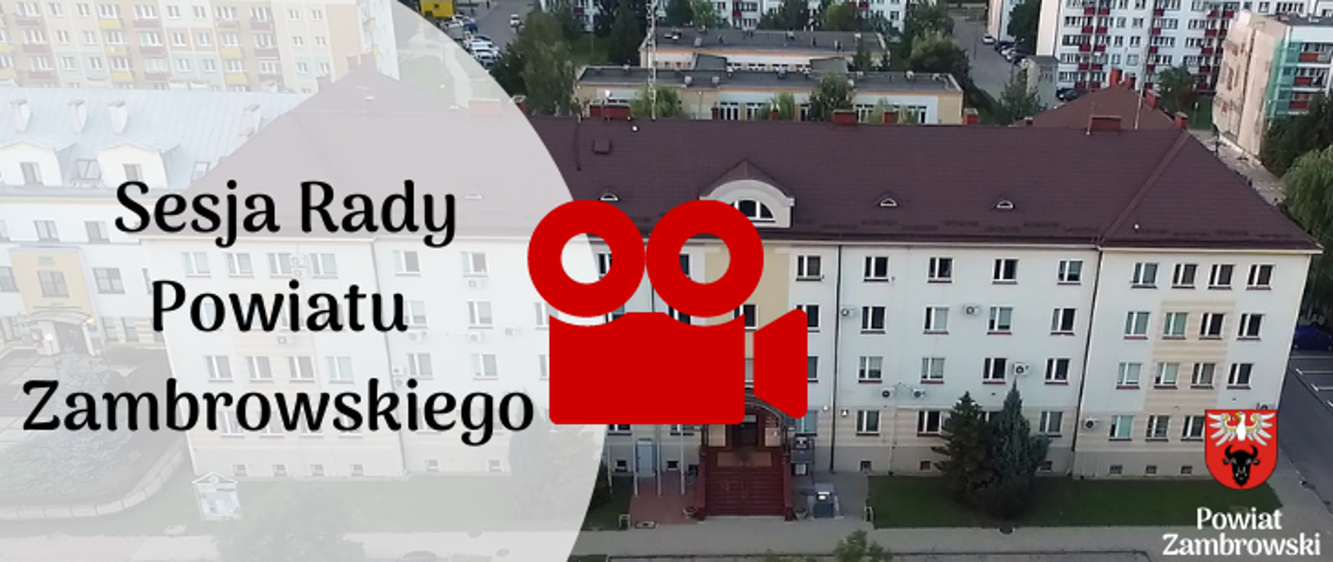 banner na którym znajduje się zdjęcie z lotu ptaka budynku Starostwa na nim połprzezroczyste tło i napis "Sesja Rady Powiatu Zambrowskiego" obok czerwona kamera, w prawym dolnym rogu logo powiatu z napisem "Powiat Zambrowski"