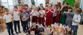 Społeczność przedszkolna pozuje z zebranymi rzeczami