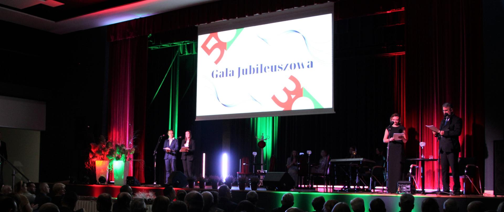 Ludzie siedzą na krzesłach w Auli podczas uroczystej gali 