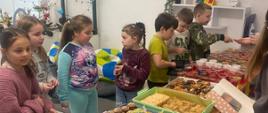 Uczniowie dokonują zakupu na kiermaszu szkolnym.