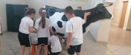 dzieci doją sztuczną krowę