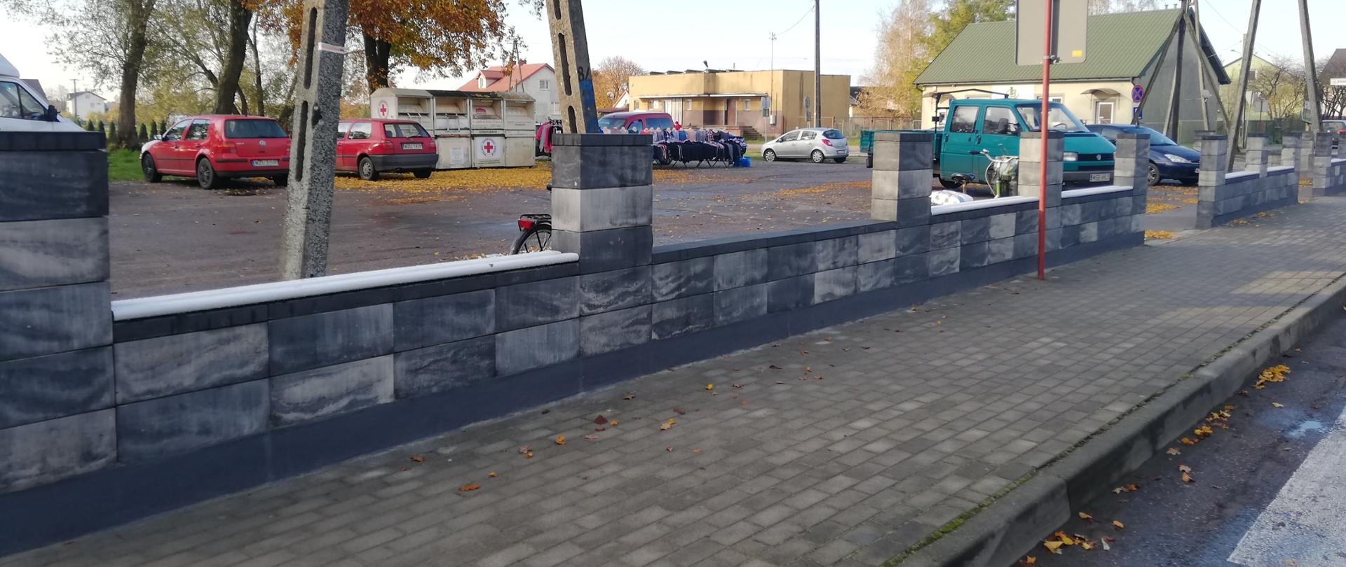 Zdjęcie przedstawia ogrodzenie parkingu gminnego przy Placu Kościuszki w Lutocinie.