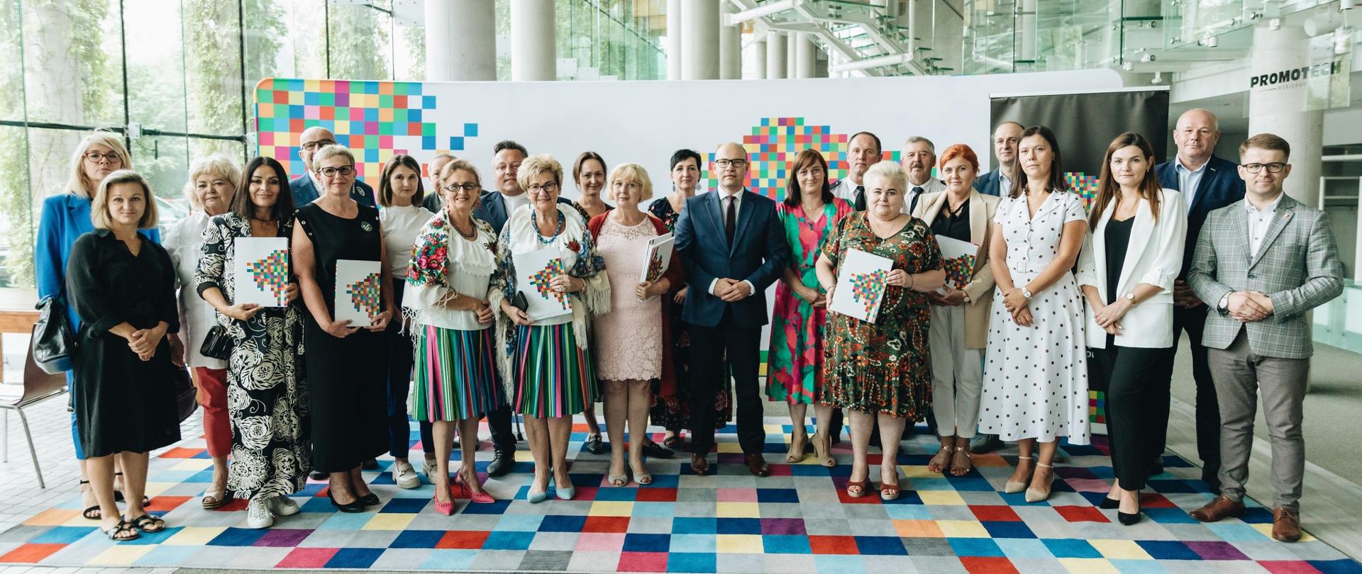 Marszałek Artur Kosicki pozuje do zdjęcia z laureatami grantów