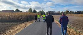 Uczestnicy odbioru drogi idą po asfalcie