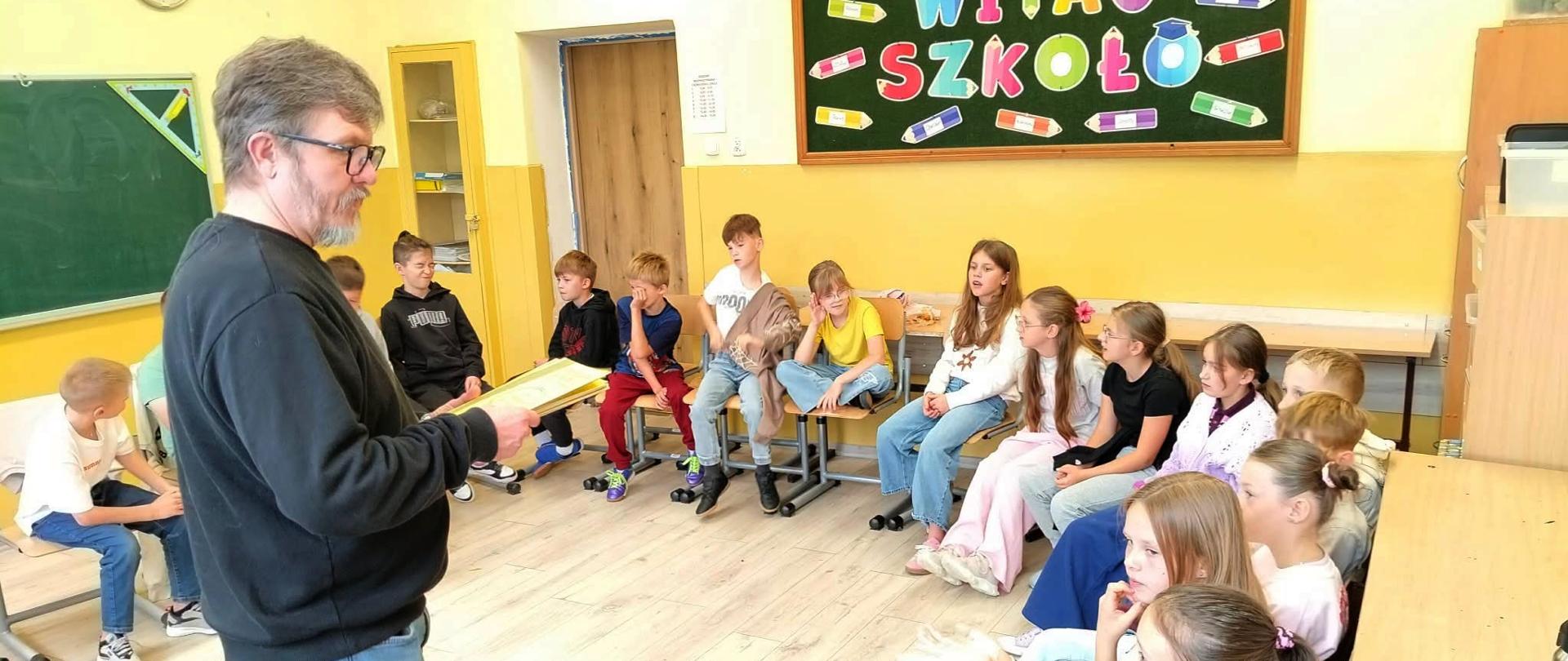 Prowadzący warsztaty rozmawia z dziećmi siedzącymi w kole w klasie szkolnej
