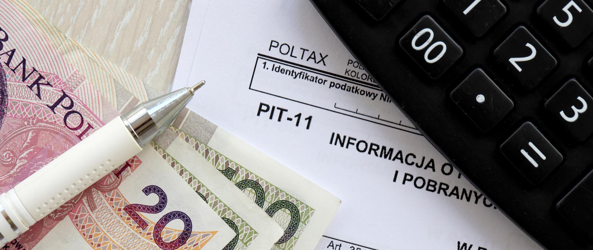 Kalkulator, długopis i polskie banknoty leżą na formularzu podatkowym PIT-11, symbolizując rozliczenie podatku i finanse osobiste.