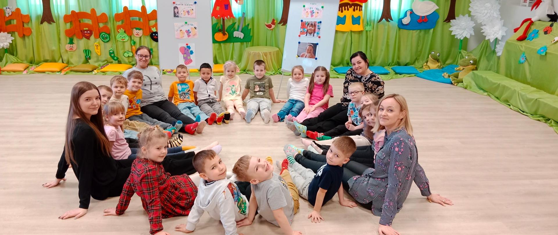 Dzieci i 4 kobiety siedzą w kole 