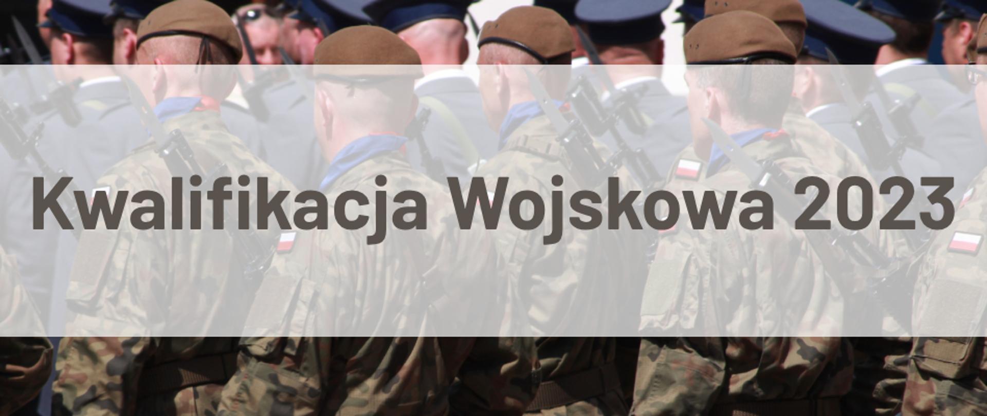 Na fotografii widzimy sylwetki żołnierzy Wojska Polskiego w mundurach maszerujących w kolumnie z karabinami, na których są bagnety. Widok z tyłu kolumny. 