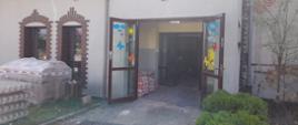 Otwarte drzwi b białym budynku z ceglanymi obramowaniami okien