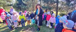 Dzieci i grono pedagogiczne z Gminnego przedszkola podczas czynności sadzenia pamiątkowego dębu katyńskiego