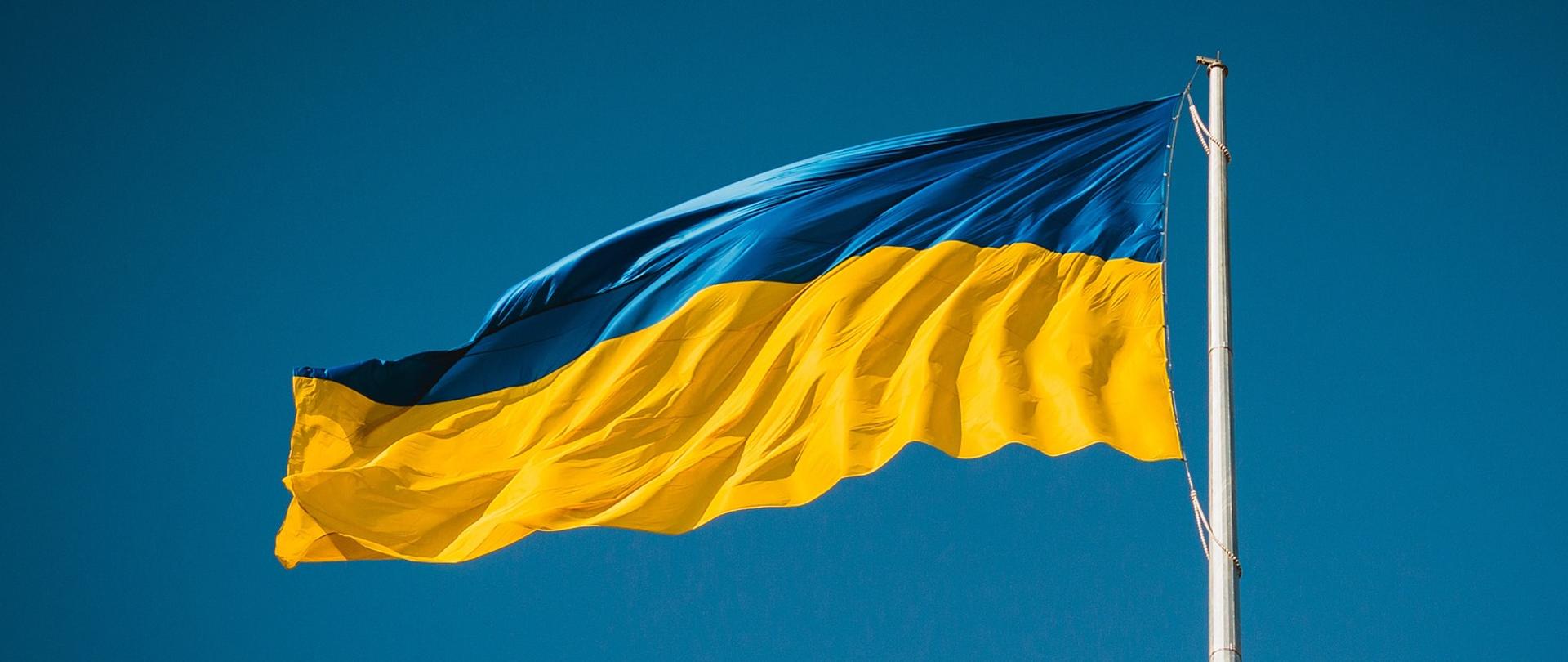 Przyczepiona do masztu niebiesko-żółta flaga Ukrainy powiewająca na wietrze