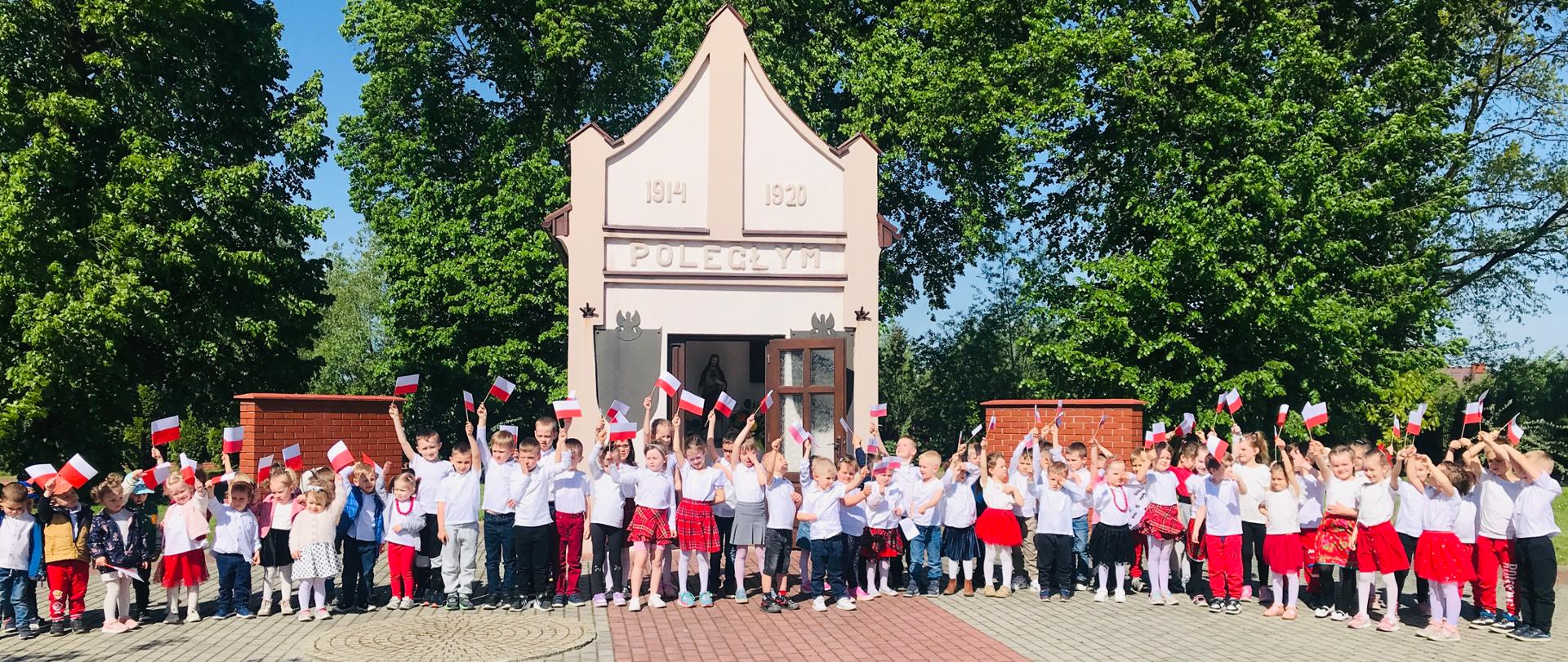 Dzieci z flagami Polski spacerują w Chorzelowie z okazji Święta Flagi.