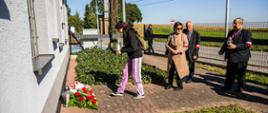 Przedstawiciele władz kombatanckich składają wieniec i znicze pod tablicą pamiątkową przy budynku poczty w Koniuszy