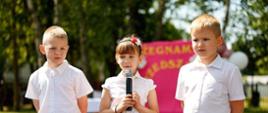 Przy głosie absolwentka Przedszkola, obok niej stoi dwóch kolegów
