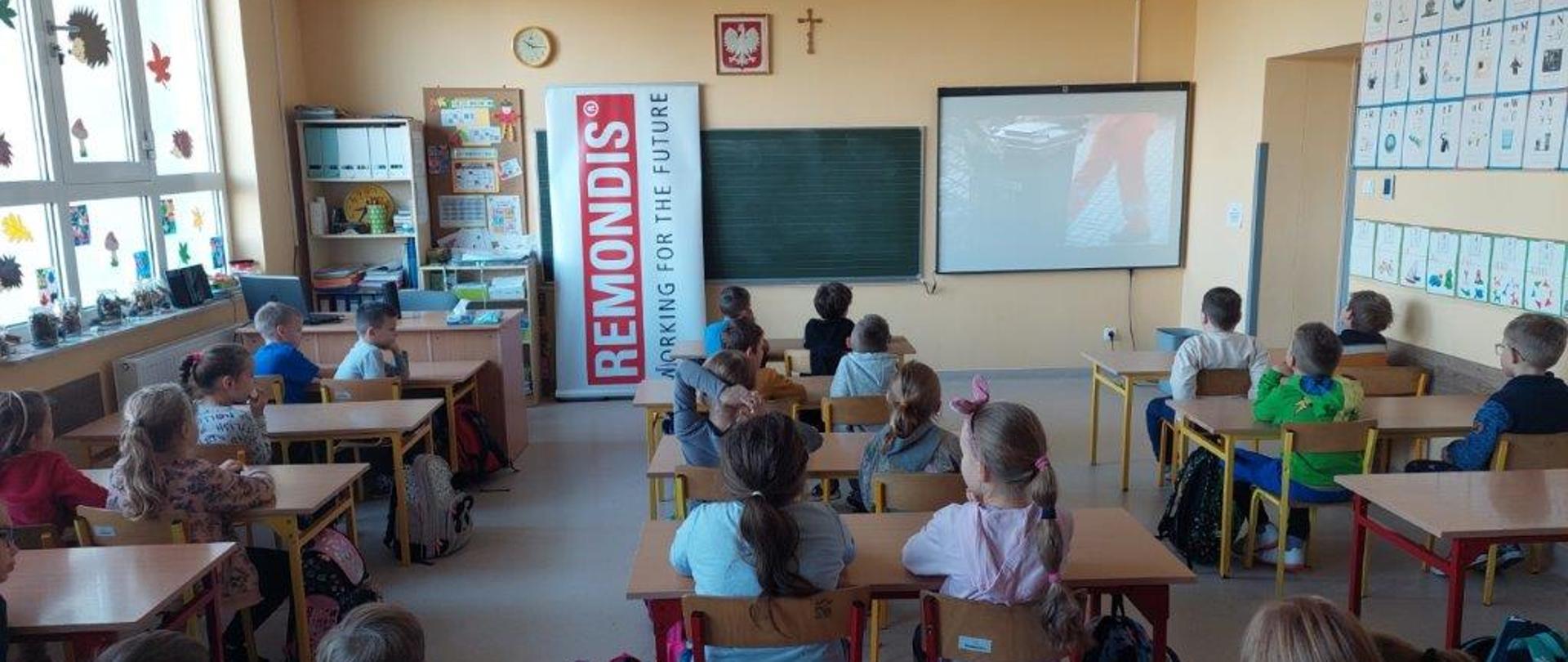 Zajęcia w szkole. Dzieci na sali oglądają obrazy na ekranie rzutnika
