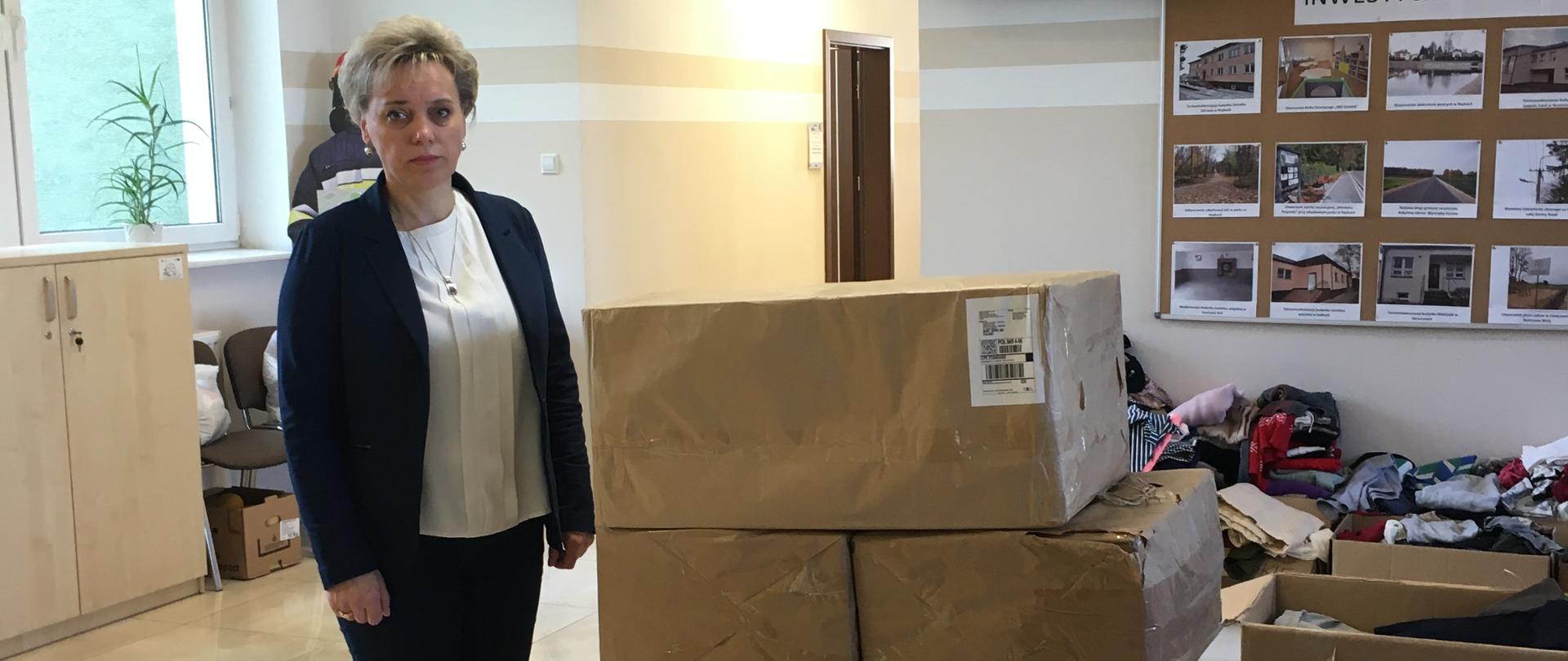 Wójt Apolonia Stasiuk stoi obok paczek przesłanych przez darczyńców z Hiszpanii dla uchodźców z Ukrainy