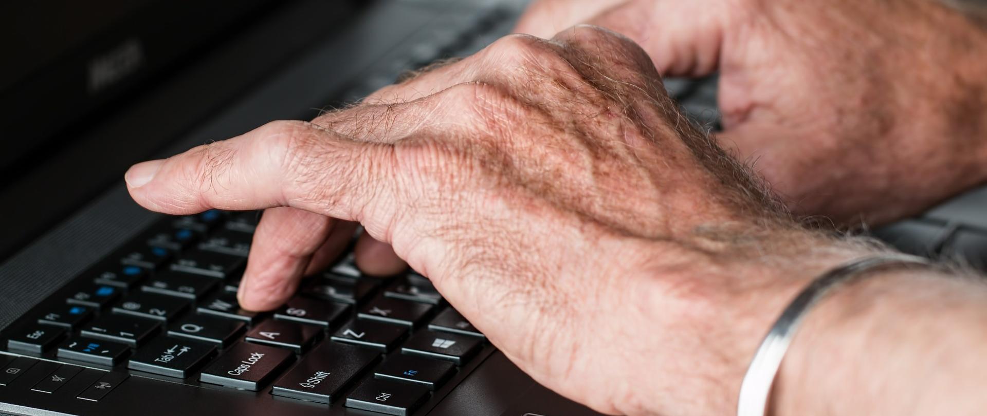ręce seniora na klawiaturze komputera