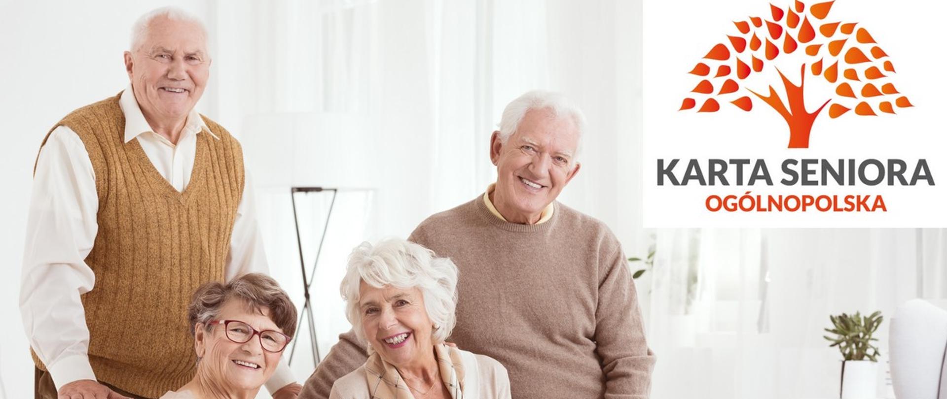 Zdjęcie przedstawia dwie seniorki i dwóch seniorów, którzy pozują uśmiechnięci w jasnym wnętrzu mieszkania. W prawym górnym rogu zdjęcia znajduje się logotyp programu.