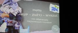 Prezentacja PUK -slajd wprowadzający. Na szarym tle zdjęcie mężczyzny trzymającego stos ubrań, obok napis: motto KUP - ZUŻYJ - WYRZUĆ nie odpowiada najnowszym trendom