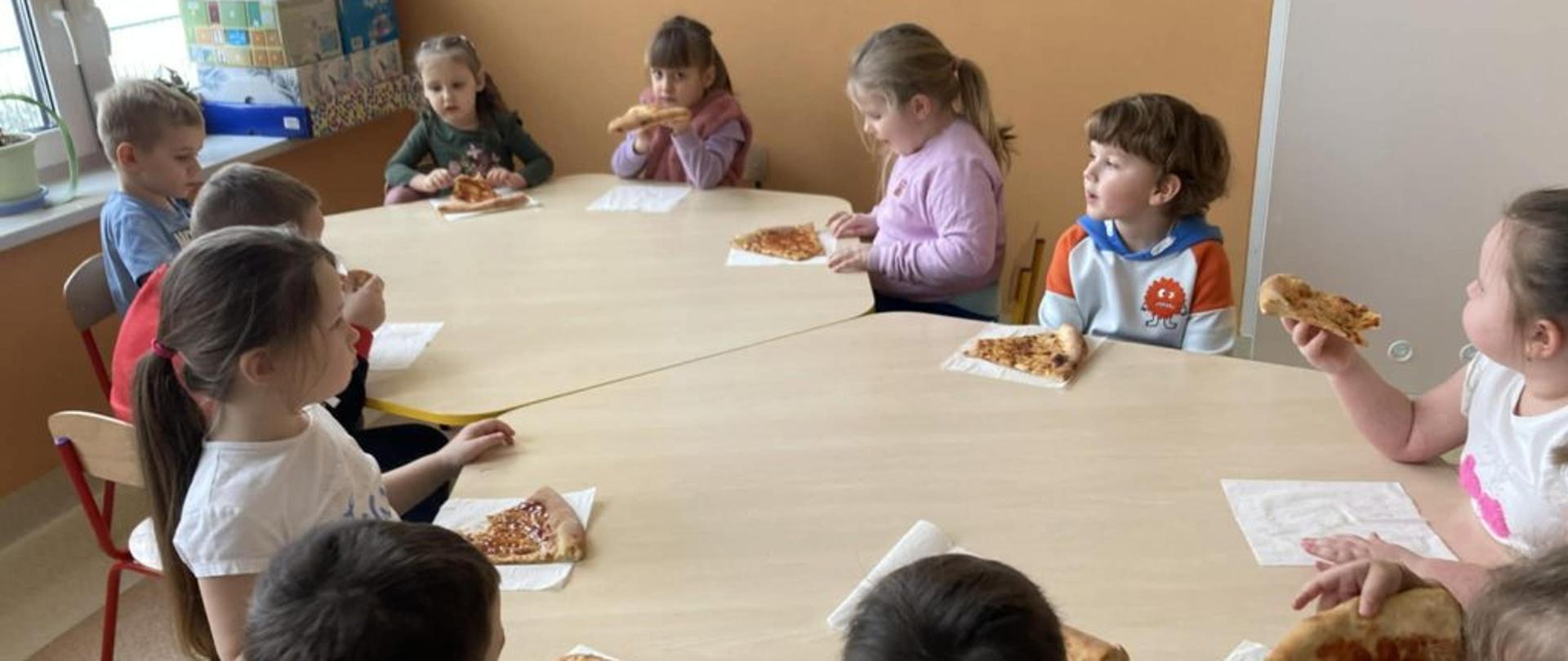 Grupa dzieci jedząca pizzę