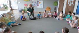 Uczniowie siedzą w kole, prowadząca warsztaty prezentuje wyroby z gliny