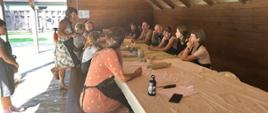 Uczestnicy siedzą przy stole, na którym znajdują się warsztatowe przybory