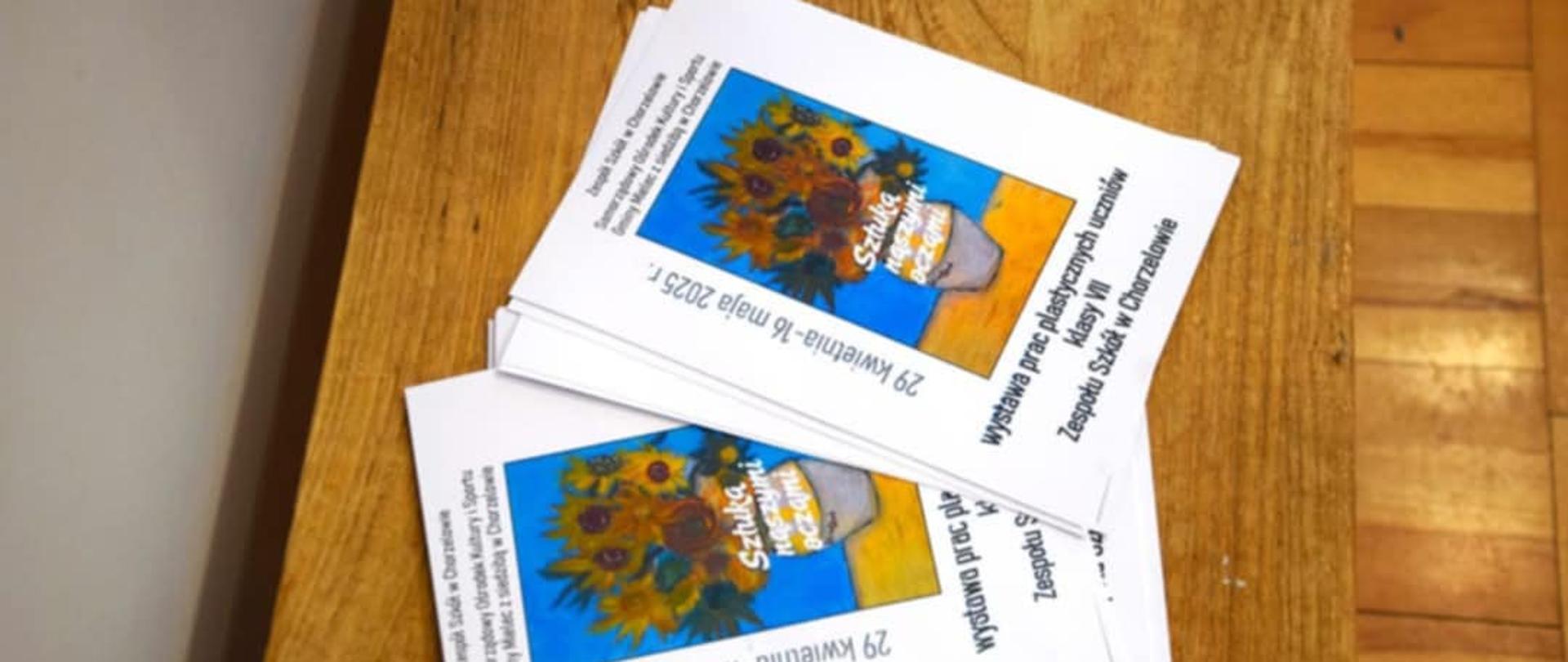 Na zdjęciu znajdują się broszury, zawierające informacje dotyczące wernisażu uczniów klasy 7