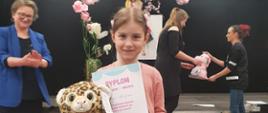 Młoda solistka prezentuje dyplom i otrzymaną maskotkę 