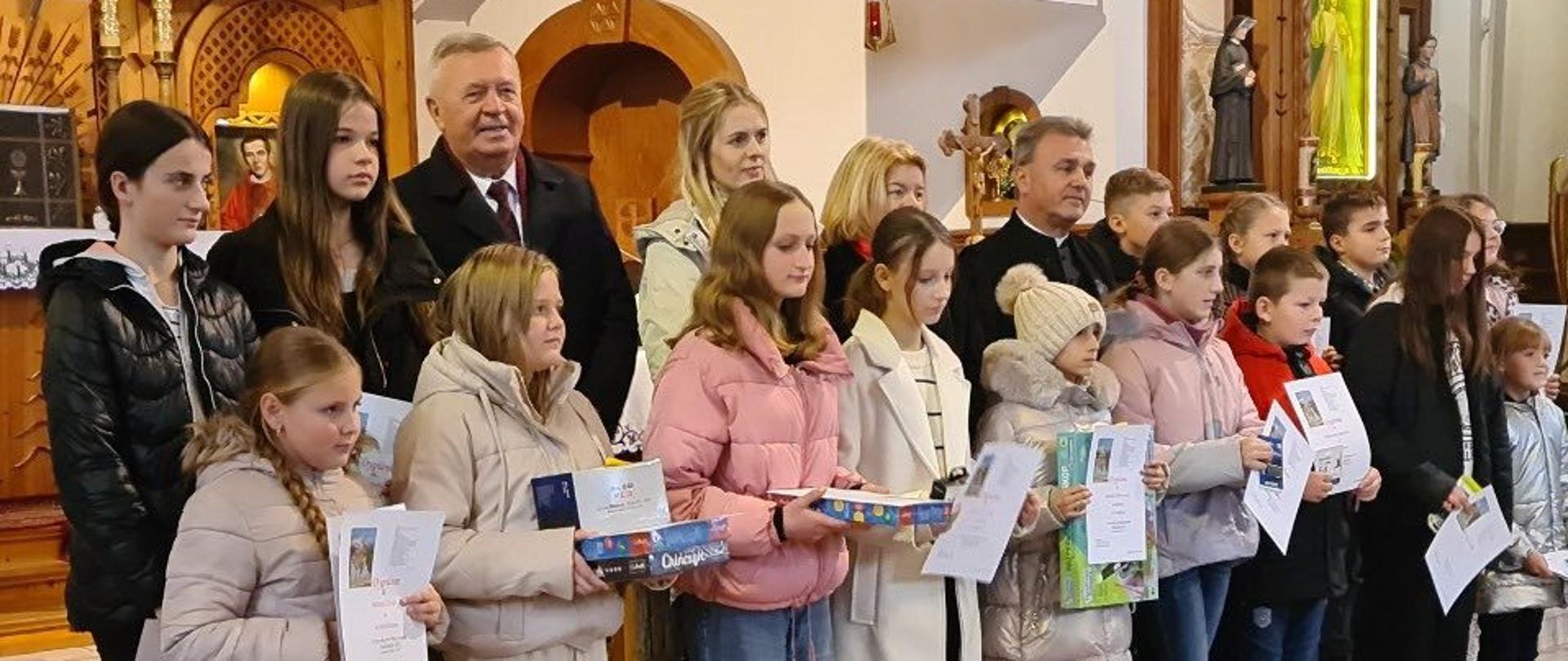 Uczennica naszej szkoły wspólnie z narodzonymi uczestnikami konkursu ustawiona przy ołtarzu do wspólnego zdjęcia.