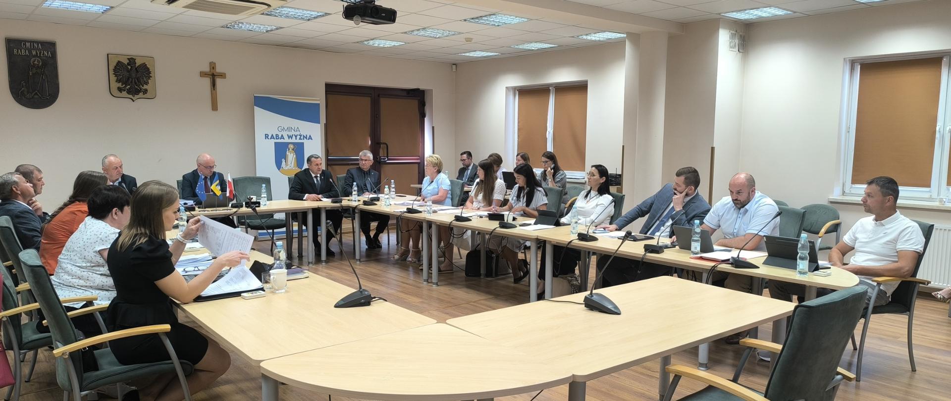 Sesja Rady Gminy 26.06.2025r., zdjęcie sali obrad podczas trwania sesji. Obecni Radni przy stole oraz Wójt i Zastępca Wójta.
