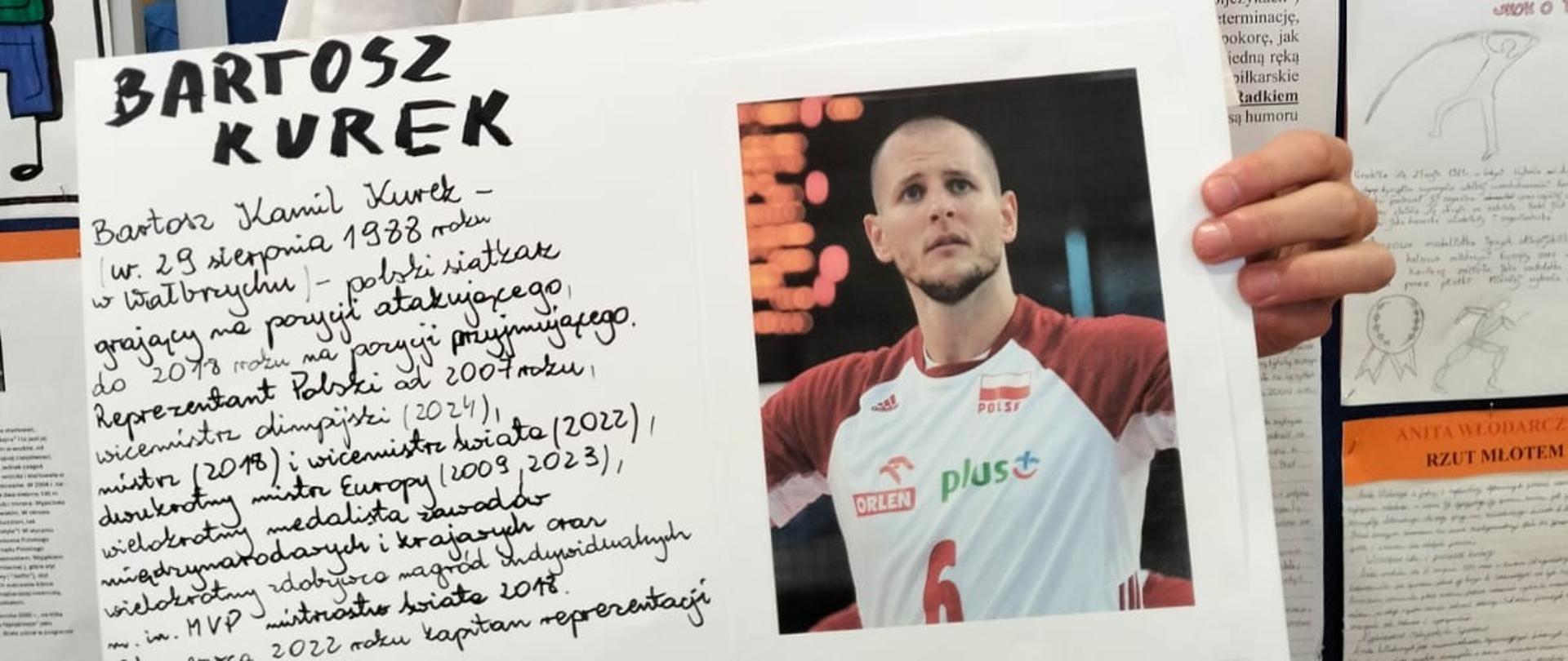Uczeń trzyma w ręku plakat prezentujący znanego siatkarza Bartosza Kurka wraz z jego zdjęciem i życiorysem