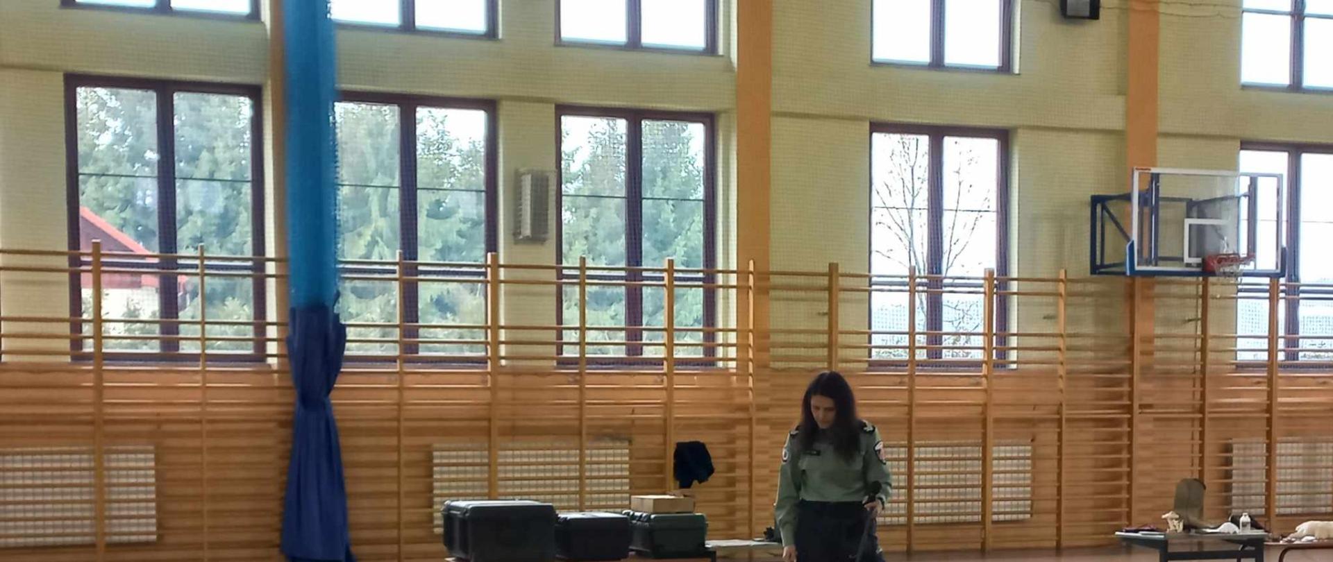 Na środku hali sportowej funkcjonariuszka Służb Celno- Skarbowych w Krakowie z psem tropiącym.