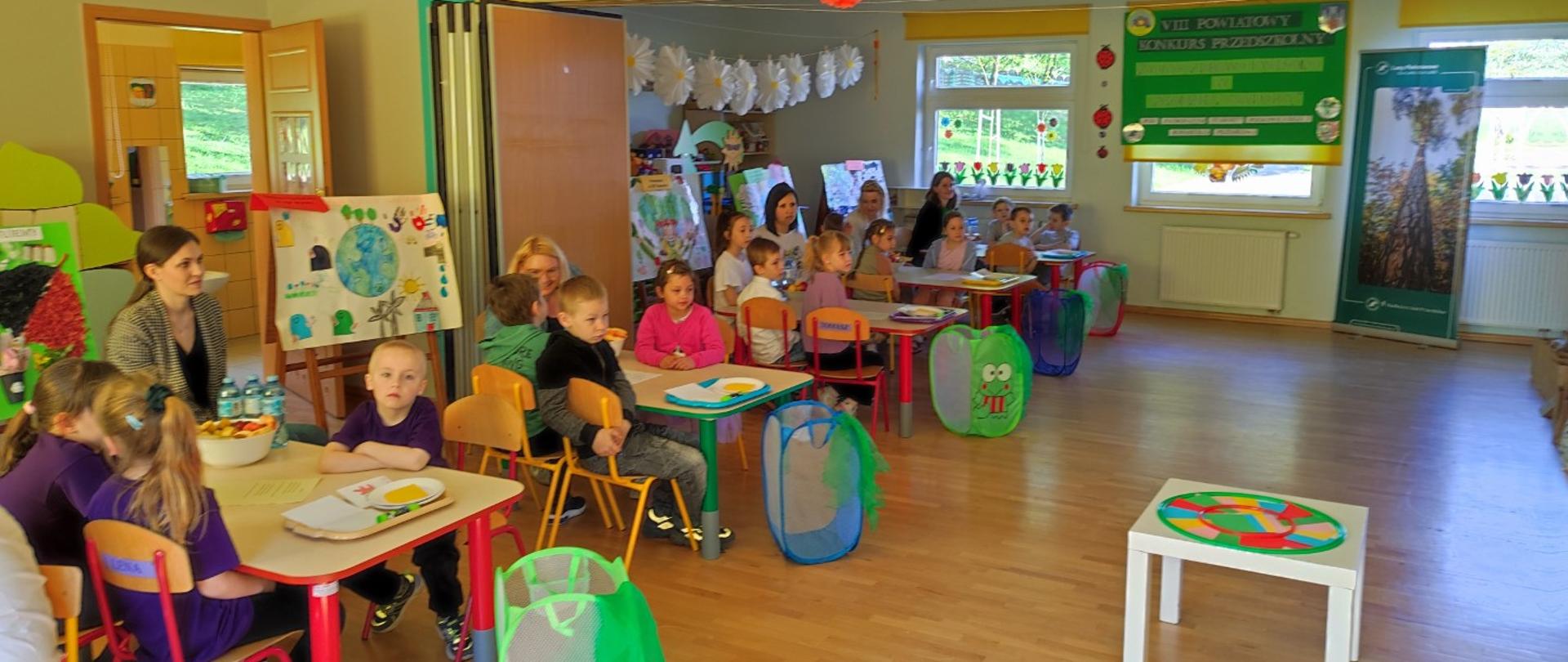 Dzieci w przedszkolu siedzą przy stolikach
