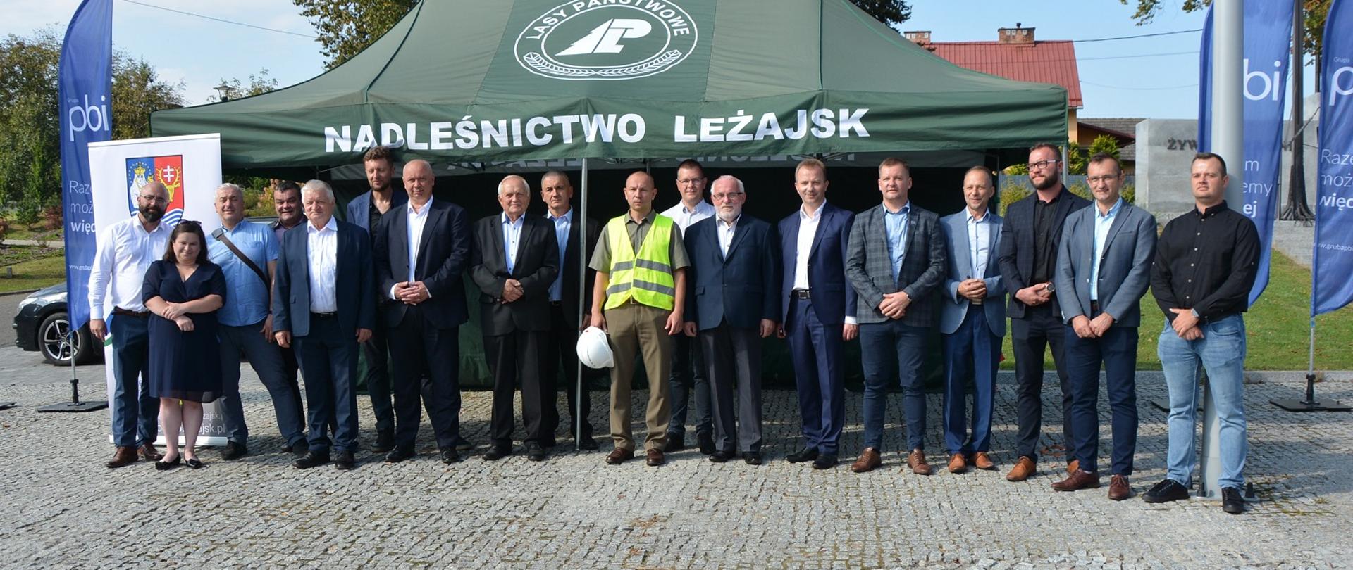 Mężczyźni i jedna kobieta stoją w rzędzie i pozują do zdjęcia, w tle zielony namiot z białym napisem Nadleśnictwo Leżajsk