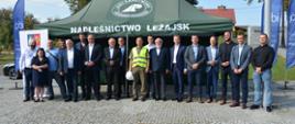 Mężczyźni i jedna kobieta stoją w rzędzie i pozują do zdjęcia, w tle zielony namiot z białym napisem Nadleśnictwo Leżajsk