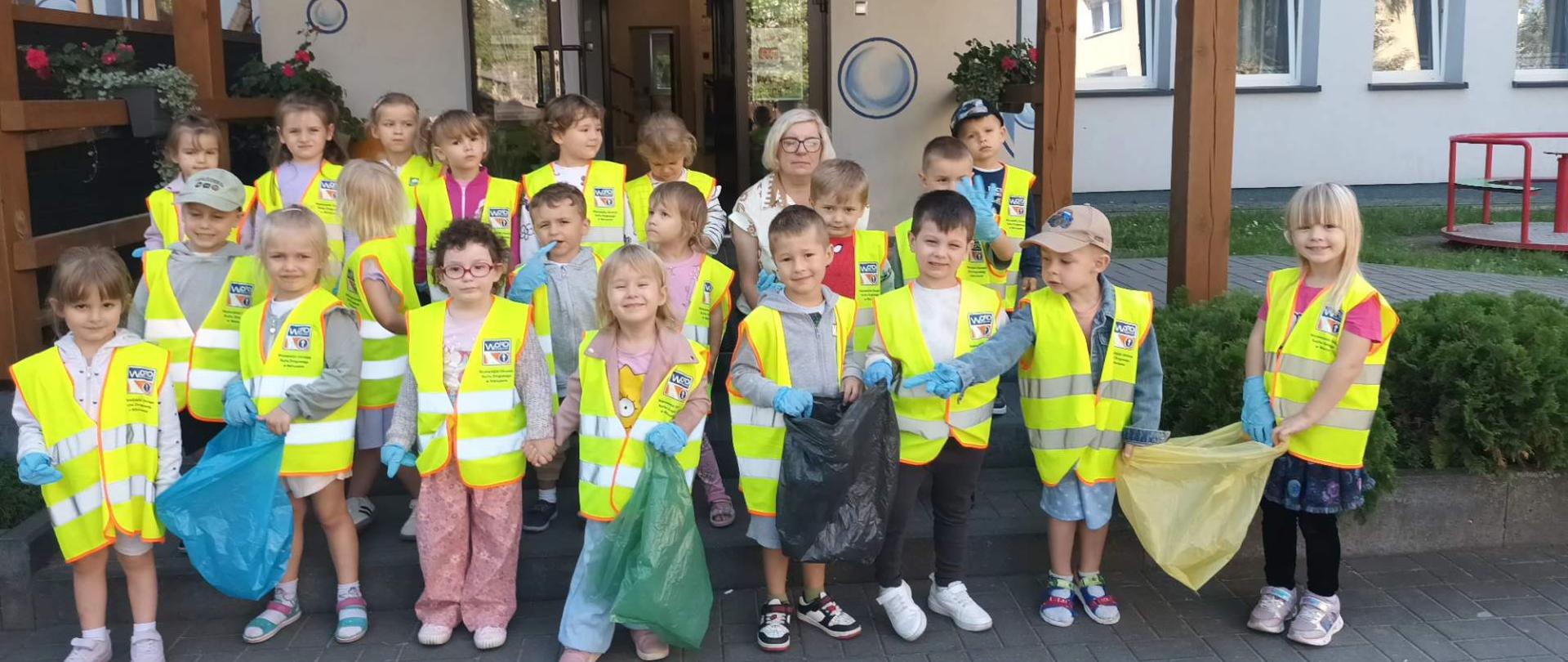 Grupa dzieci w kamizelkach odblaskowych i z workami na śmieci