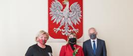 trzy osoby na tle godła