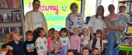grupka dzieci z wizytą w bibliotece, rysują na tablicy interaktywnej
