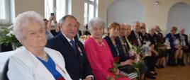 Siedzący jubilaci z kwiatami i upominkami