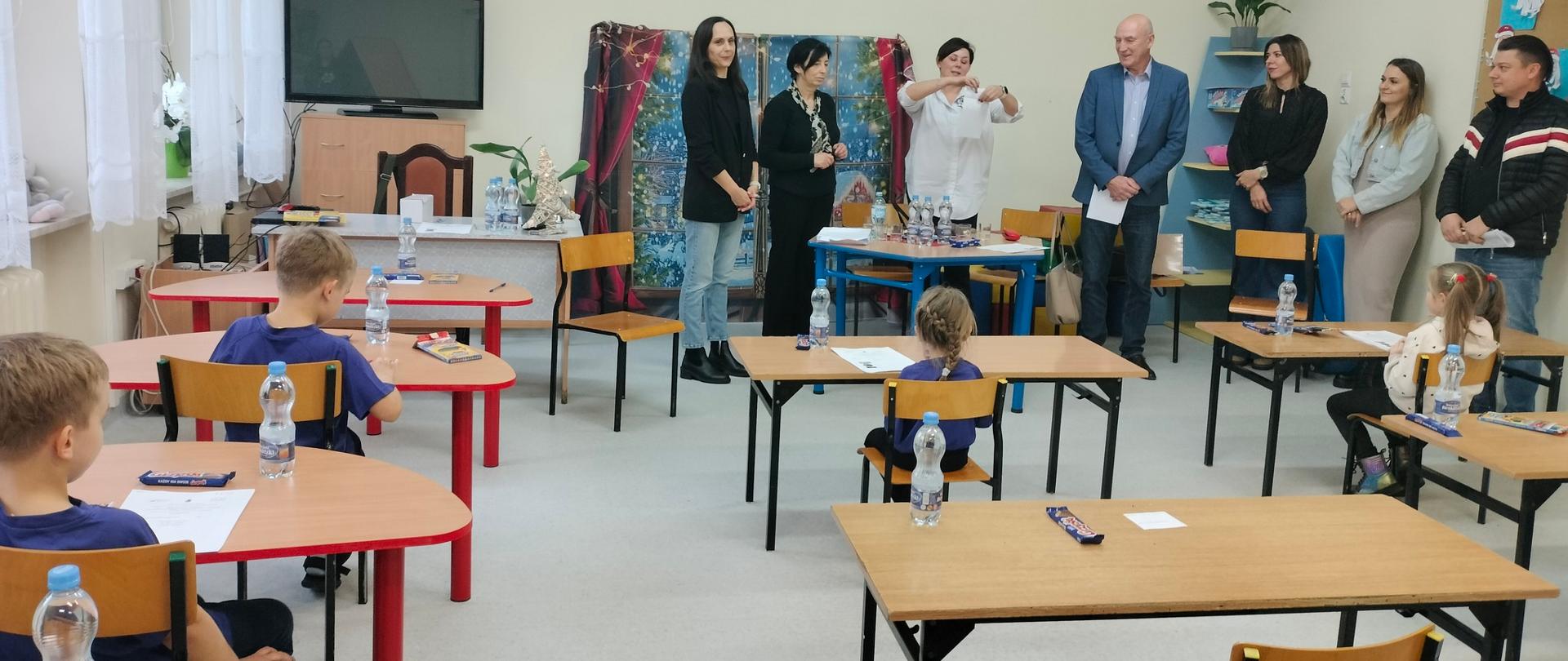 dzieci w ławkach i 7 osób dorosłych